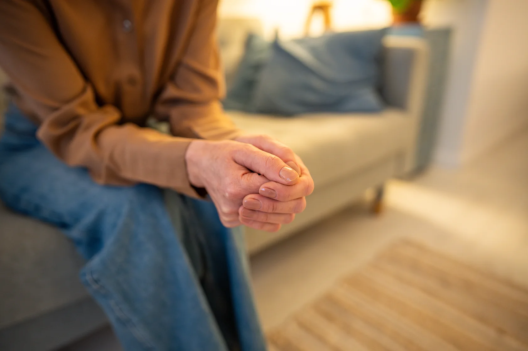 Worried female hands clasped in closed vulnerable posture on mental health consultation